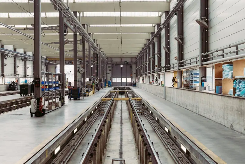 Long industrial hall with a central track, workstations and overhead lights — WindBar.ai CHROMA WING