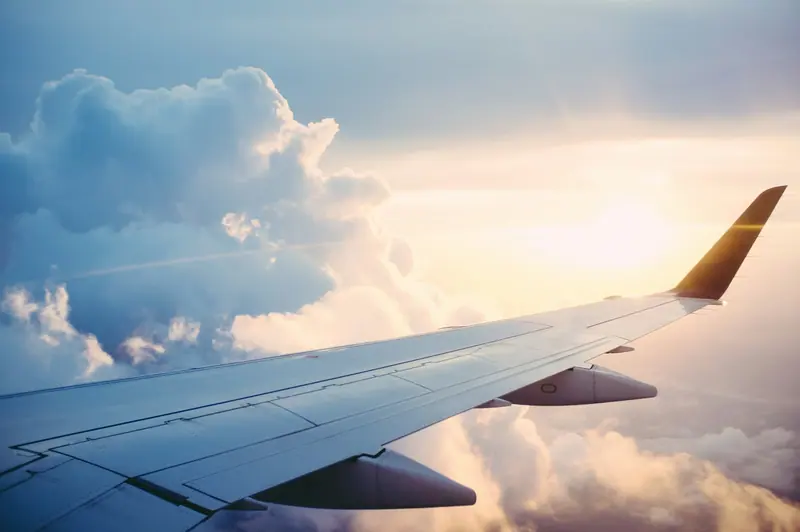 Airplane wing above clouds (Unsplash stock) — WindBar.ai D91 Voyagers