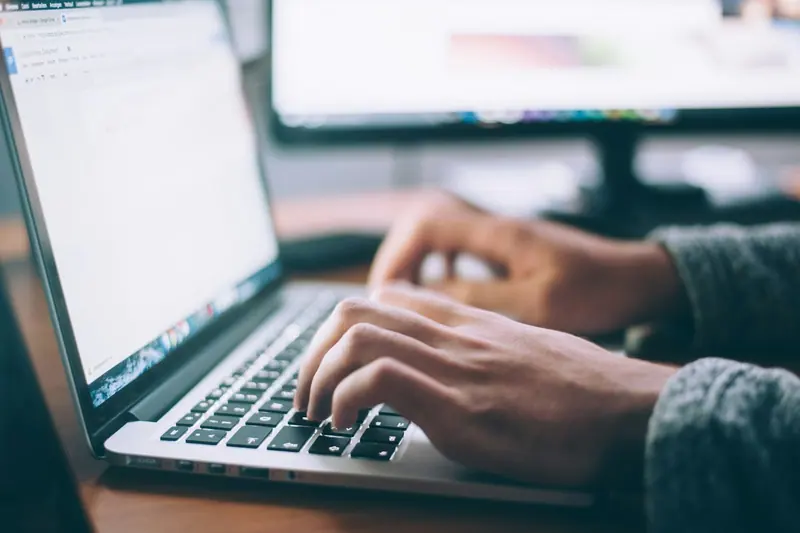 Person typing on laptop with coffee (Unsplash stock) — WindBar.ai D91 Voyagers