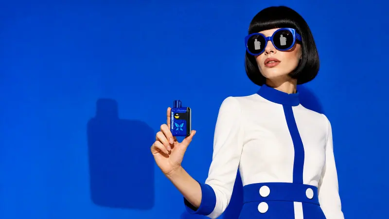 Mod-styled adult woman holding a WINDBAR SPECTRUM in Cobalt Blue against a blue wall (WindBar.ai)